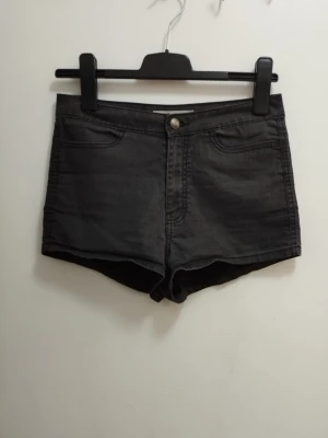 Shorts hot pants hög midja med fickor - Snygga mörkgrå denimshorts med klassisk femficksdesign, hög midja och knappstängning framtill. Shortsen har en rak passform och är perfekta för varma dagar. Materialet är slitstarkt och ger en cool vardagslook. För mått se bilderna. Kolla gärna mina andra annonser <3