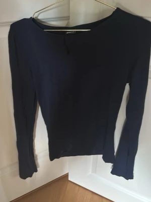 Mörkblå långärmad topp Gina Tricot - En enkel och stilren mörkblå långärmad topp från Gina Tricot. Modellen har en rund halsringning och är figurnära i passformen. Perfekt att matcha med jeans eller kjol för en clean look.
