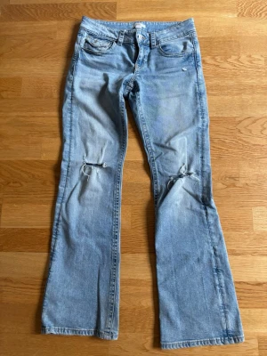 Ljusblåa bootcut jeans med hål - Super snygga ljusblåa bootcut jeans med hål i båda knäna samt lågmidjad från gina tricot young!!