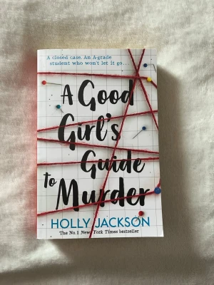 A Good Girl's Guide to Murder - Spännande pocketbok med vit framsida, rutmönster och röda trådar som ger true crime-vibbar. Titeln är tryckt i svart och blått, och boken är skriven av Holly Jackson. Perfekt för dig som gillar mysterier och thrillers.
