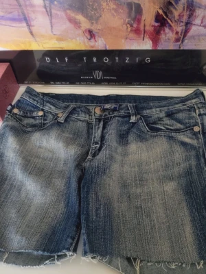 Victoria Beckham Jeansshorts 28" Rock & Republic rhinestones - Säljer ett par blå jeansshorts från Victoria Beckham med slitna kanter och snyggt tvättad look. rhinestones på bakfickorna str S/M -- 28" för Rock & Republic rhinestones shorts mått se bilder jätte fint skick  ♥️ 