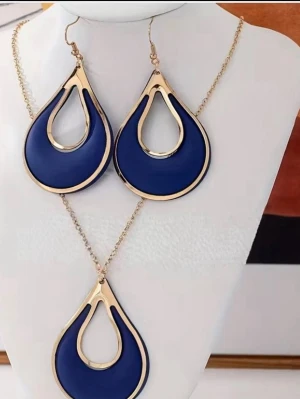 Blått smyckeset med droppform - Snyggt smyckeset med halsband och örhängen i droppformad design. Setet har en djupblå färg med guldfärgade kanter och kedja. Passar perfekt för dig som gillar statement-accessoarer och vill sticka ut. Materialet är metall och emaljliknande yta.