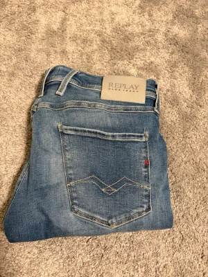 Replay - Snygga blå jeans från Replay med klassisk femficksdesign och diskreta slitningar. Jeansen har raka ben och en ljus tvätt, samt detaljerad söm på bakfickan. Perfekta för en avslappnad och trendig stil. Storlek 30/30, kom med bud!!