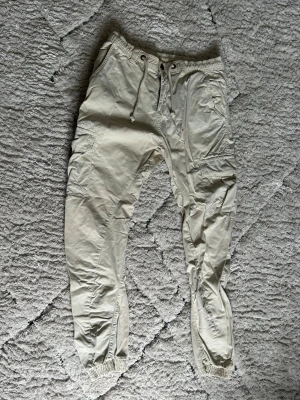 Urban Classics | Cargo byxor beige - Säljer mina cargo byxor. Jag har haft de liggandes hemma väldigt länge så kommer inte ihåg vart jag köpte de. Har inte använda värst mycket. Det finns dock ett litet hål i höger byxficka.