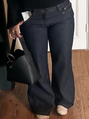 Mörkblåa vida jeans med låg midja - Snygga mörkblå jeans med låg  midja och vida ben. Klassisk femficksmodell i kraftigt denimtyg. Perfekta för dig som gillar en avslappnad men trendig look. Passar till både sneakers och boots.
