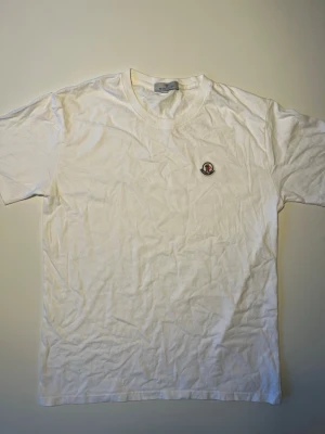 Moncler T-shirt   - Klassisk vit T-shirt från Moncler med broderad logga på bröstet. Rund halsringning, 100% bomull, avslappnad passform.  Skick: Mycket bra skick, inga hål eller fläckar.   Storlek: 3XL (passar M/L)  Material: 100% bomull   Öppen för bud/prisförslag 😊 Skickas snabbt! 
