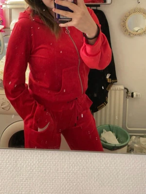 Röd velourhoodie med dragkedja - Säljer en snygg röd hoodie som slutar vid naveln och är i mjuk velour, den har dragkedja framtill och två fickor. Det är en klassisk huva och det är muddar vid ärmslut och nederkant (Se bilder). Den är från Lager157 och är i storlek Medium. Det finns 3st fläckar på baksidan som inte är så stora och som man inte ser jättetydligt (se sista bilden). Säljes pga för liten🤩☺️
