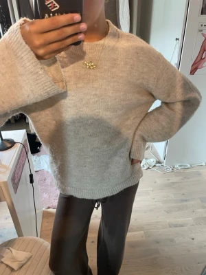 Beige oversized stickad tröja - Mysig beige stickad tröja med oversized passform och långa ärmar. Tröjan har rund halsringning och ribbade muddar vid ärmslut och nederkant. Perfekt för lager på lager och chill dagar.