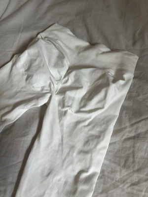 Vita  leggings från DFINE - Säljer ett par vita seamless leggings från DFINE. De har hög midja med bred ribbad kant och är tillverkade i ett stretchigt material. Perfekta för träning eller chill. 