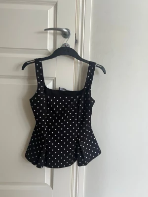 Svart prickig linnetopp från primark - Snygg svart linnetopp från primark i storlek xs, breda band och är utsvängd i slutet. 
