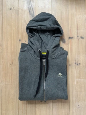 Mörkgrå zip hoodie från Moose Knuckles - Säljer en mörkgrå hoodie från Moose Knuckles i storlek L/ M. Inga konstigheter, du får varmt höra av dig vid frågor! 