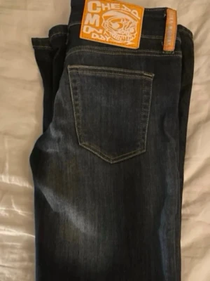 Mörkblåa Cheap Monday jeans - Säljer ett par mörkblåa jeans från Cheap Monday med klassisk femficksmodell och tydlig logga med döskalle på bakfickan. Jeansen har raka ben och är tillverkade i denim med snygg tvättad effekt. Perfekta för en avslappnad och trendig stil.