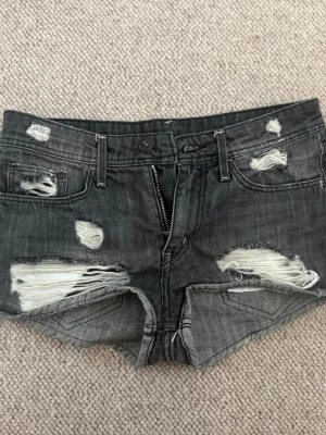 Grå slitna jeansshorts  - Snygga grå jeansshorts med trasiga och slitna detaljer framtill och baktill. Köptes på plick oxh användts några gånger men har inga tecken på användning. 