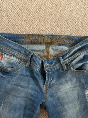 Blåa jeans - Säljer ett par blå jeans med slitna detaljer. Jeansen har klassisk femficksmodell, ljusa tvättade partier och snygga kontrastsömmar. Säljer pga dom aldrig har kommit till användning. Dom är i nytt skick utan defekter. 