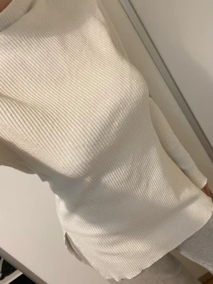 Tröja med slits  - Snygg vit ribbad tröja med lång ärm och hög hals. Tröjan har en rak passform och slitsar i sidorna. Står inte storlek men passar S/M