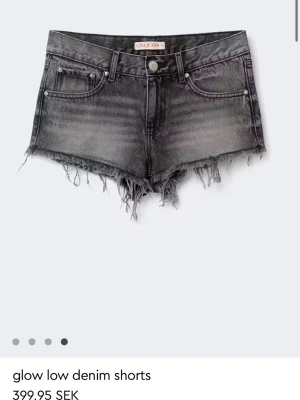 Svarta denimshorts med låg midja - Säljer ett par svarta denimshorts med låg midja och rå kant. Klassisk femficksmodell med knapp och dragkedja framtill. Perfekta till sommaren och lätta att matcha med olika toppar.