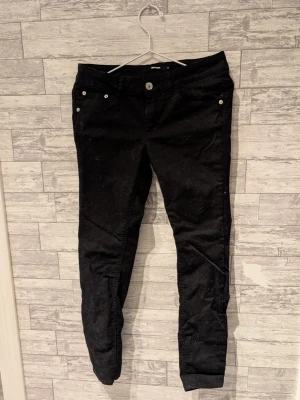 Svarta skinny jeans från BikBok - Snygga svarta skinny jeans från BikBok med silverfärgade knappar och nitar. Jeansen har klassisk femficksdesign och smal passform som sitter tight längs benen. Perfekta för en trendig och stilren look.
