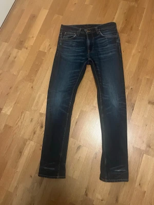 Nudie lean Dean raw denim - Snygga mörkblå slim fit jeans med diskreta slitningar och kontrastsömmar. Klassisk femficksmodell med normal midja och raka ben. Jeansen har riktigt goa slitningar och inga deffekter och storleken är w32-l34