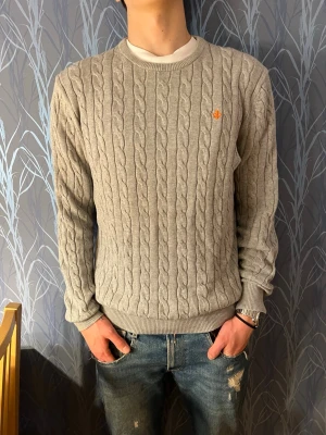 Grå kabelstickad tröja från morris - ‼️Tröjan är XL men passar även L‼️  Nu säljer jag denna kabelstickade morriströjan i ett mycket bra skick. Inget tecken på användning och perfekt till den kommande våren. Modellen är 182 cm