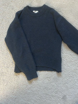 Mörkblå stickad tröja Gina Tricot - Mysig mörkblå stickad tröja från Gina Tricot med rund halsringning och ribbade muddar. Perfekt för lager-på-lager och enkel att matcha med jeans eller kjol. Klassisk modell med rak passform och lång ärm.