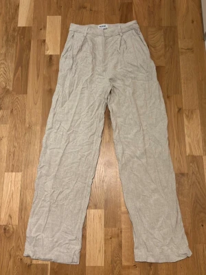 Beiga linnebyxor från Weekday - Snygga och luftiga beiga linnebyxor från Weekday med raka ben och hög midja. Byxorna har sidfickor och är tillverkade i ett tunt, svalt linnematerial som passar perfekt för varma dagar. Enkel och stilren design som är lätt att matcha.