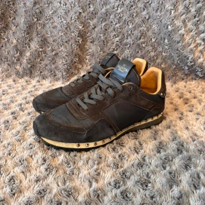 Valentino Garavani Rockrunner - Säljer ett par snygga Valentino Garavani Rockrunner i mörkblå färg, storlek 44. Klassisk modell med mocka/nylon och rockstud-detaljer längs sulan. Skick: Bra använt skick. Inga större defekter eller hål. OBS: 2 nitar saknas (1 på varje sko) – inget som påverkar användning och syns knappt när man har dem på. • Storlek: 44 • Färg: Mörkblå • Pris: 1000 kr • Inga box eller dustbag medföljer Nypris låg runt 6 000–7 000 kr. Perfekta vardagssneakers från Valentino till ett riktigt bra pris. 