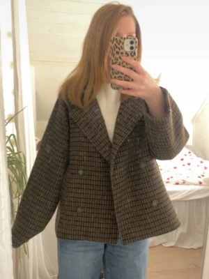 Brunrutig kappa med bred krage - Säljer en brunrutig kappa med bred krage och dubbelknäppning.