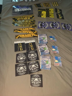 Samling AIK och supporterklistermärken och andra olika klistermärken  - Stor samling klistermärken med AIK-tema och supporterdesigns. Flera motiv i svart, gult, blått och vitt, bland annat AIK-loggor, texter som 'Gnaget', samt olika supporterbudskap. Perfekt för att dekorera laptop, mobil eller andra ytor. Finns många andra också men skriv om pris och vad du vill ha så kan vi diskutera de