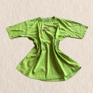 Grön t-shirt från Diesel med logga - Cool grön t-shirt från Diesel med tryckt logga både fram och bak. T-shirten har en klassisk passform och är kortärmad, perfekt för dig som vill sticka ut med en färgstark look. Materialet är mjuk bomull som känns skönt mot huden.