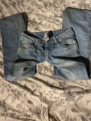 Ljusblå jeans med broderad bakficka - Snygga ljusblå jeans med klassisk femficksmodell och gylf med knapp och dragkedja. På ena bakfickan finns ett detaljerat guldigt broderi som ger extra stil. Jeansen har raka ben och är tillverkade i denim.
