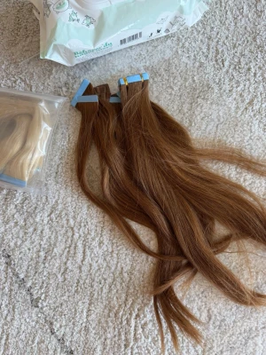 Ljusbruna tejp extensions - Säljer ljusbruna tejp extensions i äkta hår. Fästes enkelt med tejp och ger ett naturligt resultat. Perfekt för dig som vill ha längre eller fylligare hår. Färgen är en varm ljusbrun nyans och håret är rakt.