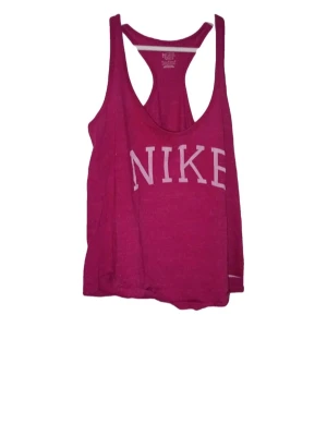 Rosa träningslinne från Nike - Snyggt rosa träningslinne från Nike med stort vitt tryck framtill. Modellen har brottarrygg och är tillverkat i ett mjukt och lätt material som passar perfekt till gymmet eller löprundan.