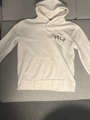Vit hoodie från Polo Ralph Lauren - Snygg vit hoodie från Polo Ralph Lauren med broderad logga på bröstet. Klassisk känguruficka framtill, dragsko i huvan och mjukt material som känns skönt mot huden. Perfekt för en avslappnad och stilren look. Säljer den då den inte passar längre. Köptes ny på outlet i USA för ungefär 1 år sedan.