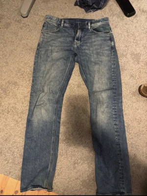 Blå raka jeans från G star  - Ett par klassiska blå jeans med raka ben. Materialet är denim i bomull och de har en tidlös tvättad look som passar till det mesta. Jeansen är i bra skick och inte så använda.