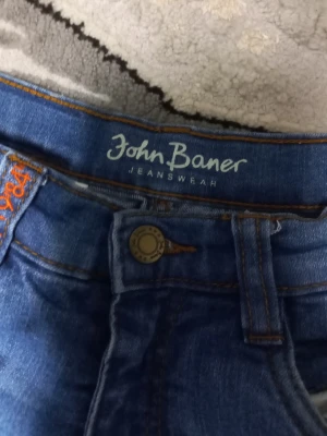 Blå jeans med raka ben och sömdetaljer - Säljer ett par blå jeans med raka ben och markerade horisontella sömmar över låren och knäna. Jeansen har klassisk femficksdesign och är gjorda i denim. Perfekta för en avslappnad och trendig look. PRIS KAN DISKUTERAS!