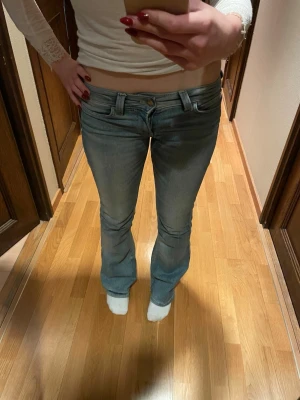 Ljusblå bootcut jeans med låg midja - Säljer ett par ljusblå bootcut jeans med låg midja och klassisk femficksdesign. Jeansen har en snygg tvättad look och är tillverkade i denim med lätt stretch. Perfekta för dig som gillar en avslappnad men trendig stil. 