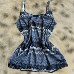 Supersöt vit topp med unik ribbad struktur och korta ärmar. Toppen har en tight passform och är stretchig, vilket gör den riktigt bekväm. Perfekt att styla till både jeans och kjol för en trendig look. Passar Xs-M, jag har storlek 40.  - Snygg linnetopp från Vero Moda med zigzag-mönster i svart, grått och vitt. Toppen har glittriga paljettprydda axelband och ärmlös design. Perfekt för dig som vill sticka ut lite extra.