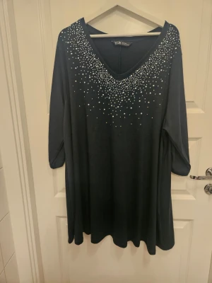 Festlig tunika med strass - Underbar mörkgrön tunika/klänning från Yours med strass i viskoskvalitet. 3/4-delsärm. Generös i storleken och i mycket gott skick. Nypris 399 kr