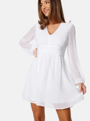 Vit kortklänning med prickigt mönster - Superfin vit kortklänning från Bubbleroom med diskret prickigt mönster, v-ringning och långa ärmar. Klänningen har markerad midja med knytband i ryggen och lätt transparent tyg. Perfekt för sommarens alla tillfällen! Hör av dig vid frågor!😊✨