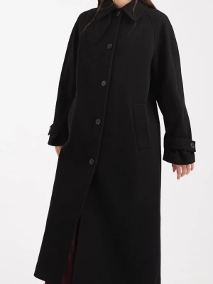 Helt ny Svart lång kappa - Helt ny, aldrig använd med lapp kvar: stilren svart lång kappa med möjlighet till hög krage eller klassik. Knäppning framtill. Kappan har raka ärmar med dekorativa spännen vid handlederna och två diskreta fickor. Tidlös. Från ASOS, polyester. Köpt för 1 139kr.