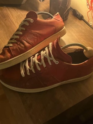 Röda Saint Laurent SL03 - Säljer ett par röda model SL03 sneakers från Saint Laurent Paris. Skorna är i läder med vita snören. Märket är präglat under sulan. Perfekta för dig som gillar exklusiva och tidlösa sneakers. Strl 43