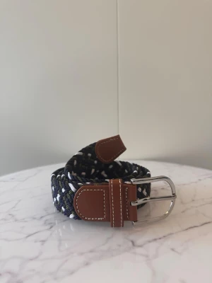 Blå grön vit flätat bälte - Tja säljer helt nya svenska klassiska flätade bälten från Bältgallerian i storlek 105cm lång och 3,5cm bred. Dem är i ett elastiskt material och finns i flera olika färger i min profil