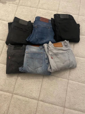Levi's och tiger of sweden jeans i olika färger - Säljer ett gäng Levi's jeans i flera färger – svart, blått, grått och ljusblått. Klassisk femficksmodell med skinnpatch bak och röda Levi's-taggen på fickan. Perfekta för dig som gillar tidlös och avslappnad stil. Alla är raka eller smala i modellen.