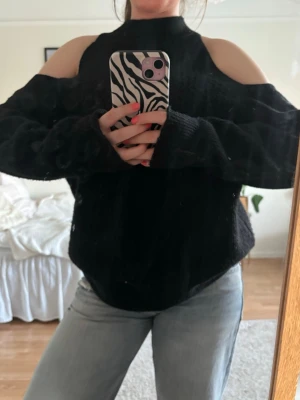 Svart stickad tröja med öppna axlar  - Säljer en svart stickad tröja med trendiga cold shoulder-detaljer och hög hals🥰 knappt använd så darför säljer jag Från märket YAS Men köpt på boozt❤️ storlek M men tycker den sitter snyggt på mig som vanligtvis har storlek S 