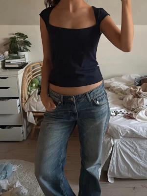 Blå topp brandy mellville  - Snygg svart topp med breda axelband och fyrkantig urringning. Modellen är figurnära och croppad, vilket ger en modern och trendig look. Perfekt att matcha med jeans eller kjol, aldrig använd .