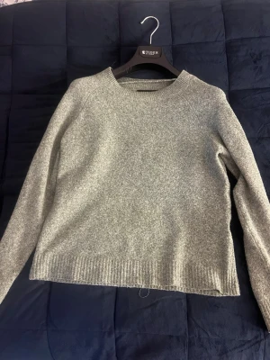 Grön stickad tröja i ullmix - Mysig grön stickad tröja från vera Moda i mjuk ullmix. Tröjan har rund halsringning, långa ärmar och ribbade muddar vid ärmslut och nederkant. Enkel och stilren design som passar perfekt till höst och vinter.