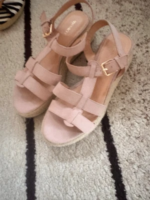 Beige/ Rosa från märket vagabond nya ! - Säljer ett par snygga beige/ rosa färgade  platåsandaler från Vagabond med flera breda remmar och justerbart spänne i guld. Sandalerna har en flätad sula i espadrillestil och öppen tå. Perfekta för sommaren eller fester och ger extra höjd med 2 cm de är använda några gånger men helt nya inga tecken användning 