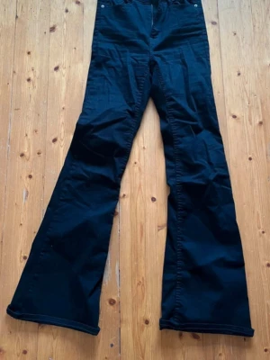 Svarta utsvängda jeans - Säljer ett par svarta jeans med utsvängda ben och hög midja. Jeansen har klassisk femficksdesign och stängs med knapp och dragkedja. Perfekta för dig som gillar retrostil och vill ha ett par riktigt snygga byxor till din garderob.