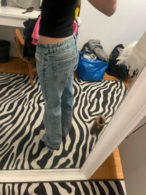 Ljusblå raka jeans med låg midja - Säljer ett par ljusblå jeans med rak passform och låg midja. Jeansen har klassiska fem fickor och är tillverkade i denim med en lätt tvättad look. Perfekta för en avslappnad och trendig stil.