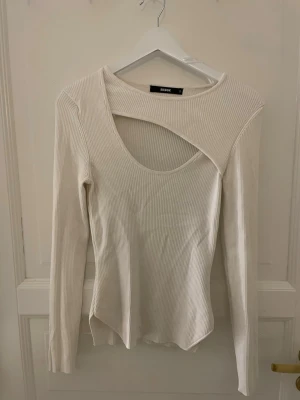 Vit ribbad topp med cut out från BikBok - Trendig vit långärmad topp från BikBok i ribbat material. Toppen har en unik cut out-detalj vid halsen och en figurnära passform. Super snygg och skön! 